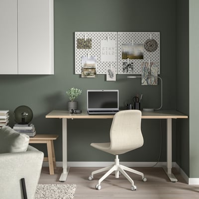 Minimalist home office: green wall, desk, chair, laptop, pegboard.