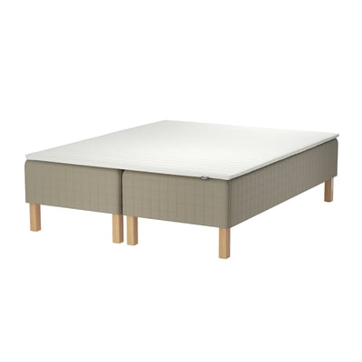 The skarer bed base a beige upholstered frame with wooden legs, holding a white mattress.