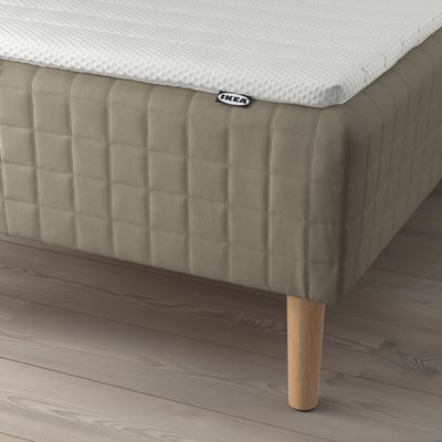 A modern bed with a SKÅRER sprung mattress on wooden legs, displaying comfort and support.