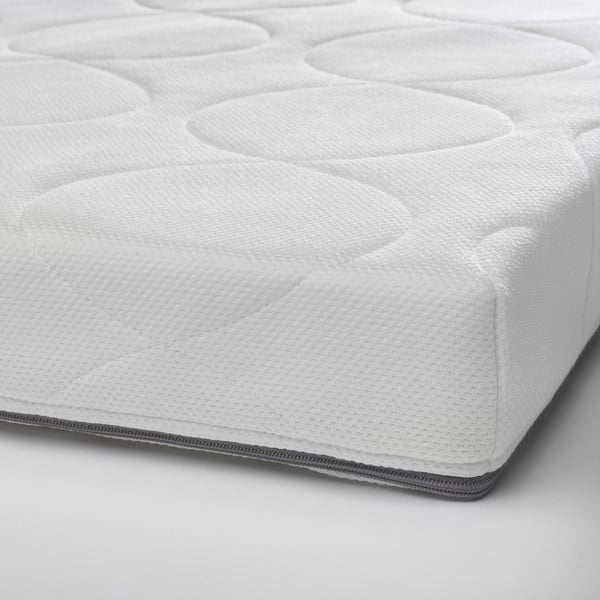 Close-up of a pure white cot mattress, soft and supportive foam with zipper layer.
