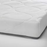 Close-up of a pure white cot mattress, soft and supportive foam with zipper layer.