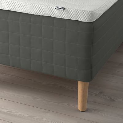 Image shows a corner of a SKOTTERUD mattress by ikea on wooden legs.