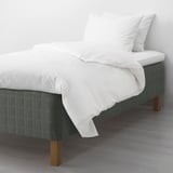 A cozy bed with SKOTTERUD mattress, pocket springs for support, white sheets, and wooden legs.