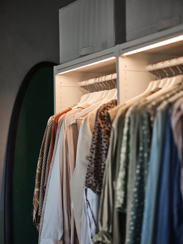 A closet with lit clothes hangers, showcasing various shirts and blouses.