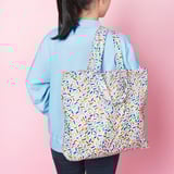 Multi-use bag with sprinkle pattern, folds into pocket, ideal for shopping/travel.