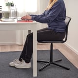 Person sitting at a white desk on a SMÄLLEN swivel chair with a gray carpet.