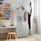 Kids room with grey SMÅSTAD wardrobe, wooden shelves, dinosaur toys, and white desk.