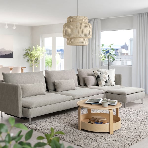 Modern living room with light grey SÖDERHAMN sofa bed, wood coffee table, large window, hanging lamp, and plants.