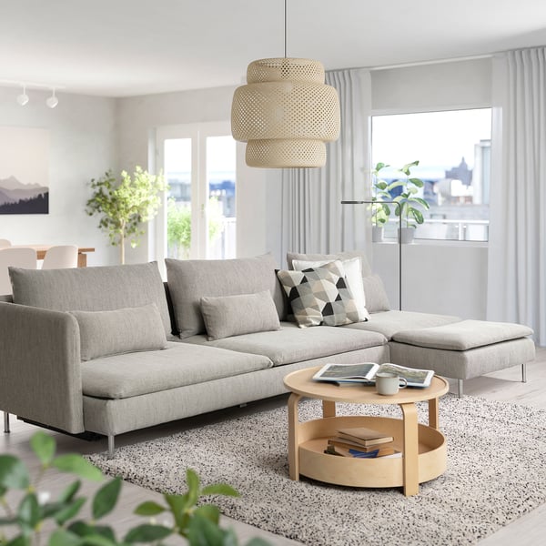 Modern living room with light grey SÖDERHAMN sofa-bed, wooden coffee table, cushioned throw pillows, large windows, and plants.