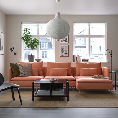 Modern living room with large orange SÖDERHAMN sectional sofa, black coffee table, large plant, white pendant lamp, and big windows.