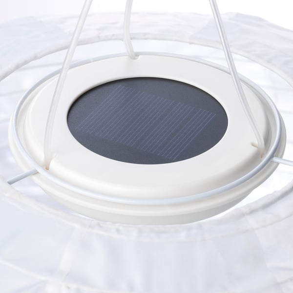 A solar-powered pendant lamp, SOLVINDEN, hangs from a cord. Its dark shade contrasts with its white frame, indicating quality and eco-friendliness.