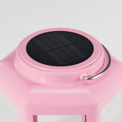 Pink solar-powered lantern with clear glass panels and metal handle. Modern design for indoor/outdoor use.