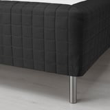 Black upholstered furniture with quilted pattern on a light wooden floor, supported by shiny metal legs.