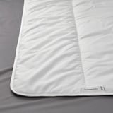 White comforter on gray bed, showcasing soft, high-quality material and craftsmanship.