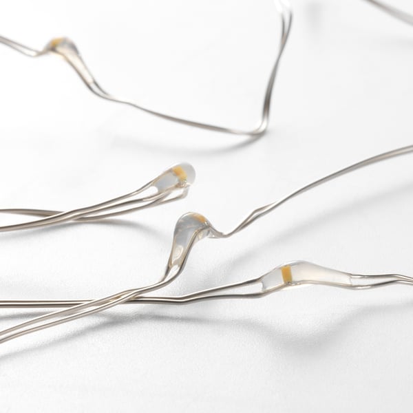 Close-up of decorative, bendable string lights with tiny glowing bulbs on a bright white background.