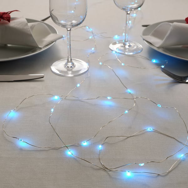 Table setting with blue led string lights, plates, glasses, and cutlery.