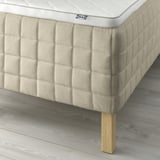 Close-up of a STUVLAND mattress on wooden legs, showcasing linen texture and pocket springs.