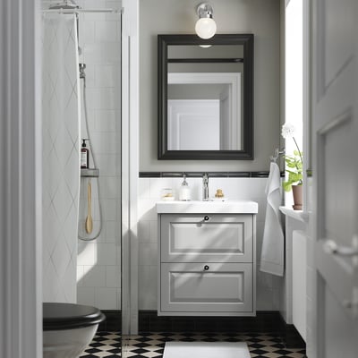 Modern bathroom with TÄNNFORSEN light grey vanity, large mirror, shower, towel, plant, and checkered floor.
