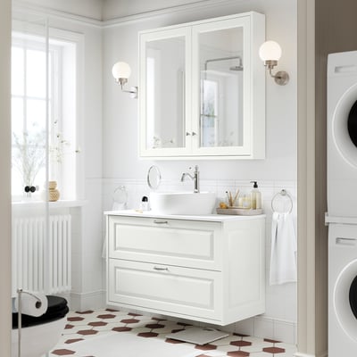 Modern white bathroom with floating cabinet. Its larger than the washing machine, featuring a round basin, two drawers, and mirrored cabinet above.