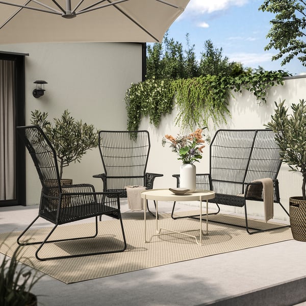 Modern patio set with black metal TALLSKÄR furniture: sofa, armchair, white coffee table. Steel and plastic wicker, ideal for outdoor relaxation.