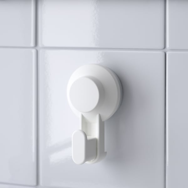 A single white TISKEN hook firmly attached to a tiled wall, showcasing its sturdy and sleek design.