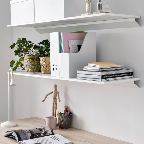 White shelves with books, files, plant pots, wooden figure, mug with pens.