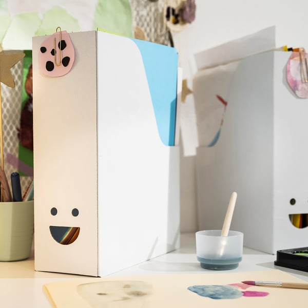 White TJABBA magazine file with smiley face on desk, with colorful contents.