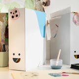 White TJABBA magazine file with smiley face on desk, with colorful contents.