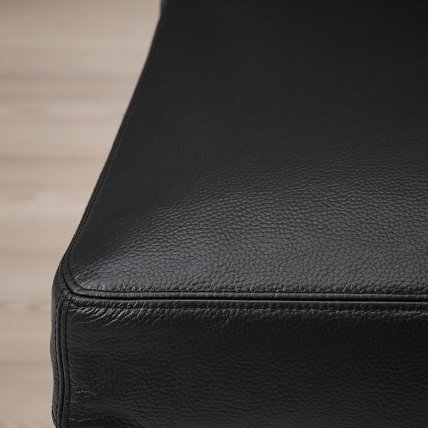 Close-up of pudgy black leather cushion, smoothly stitched edge, soft texture.
