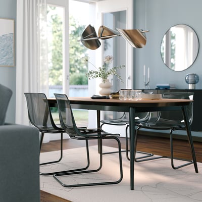 Modern dining room with rectangular walnut table, black metal chairs, pendant lamp, and mirror.