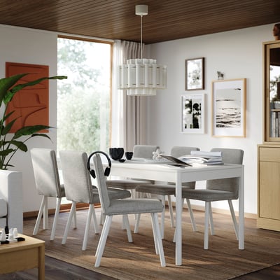 Modern dining room with white TONSTAD table, surrounded by grey chairs. Large window, hanging lamp, and wall decorations.