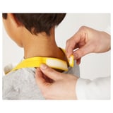 Adult adjusts childs yellow apron with touch-fastening near neck.