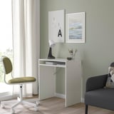 Small white TORALD desk in cozy corner; matched with olive chair, lamp, and grey sofa; simple, neat, and organized workspace.