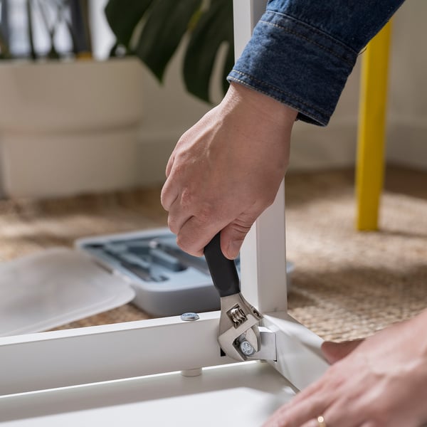 Person uses hammer from TRIXIG toolbox to assemble furniture, showing diy functionality.