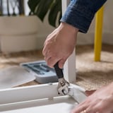 Person uses hammer from TRIXIG toolbox to assemble furniture, showing diy functionality.