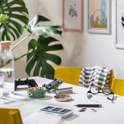 Workspace table with TRIXIG green toolbox, screwdriver set, glasses, water, plant. Compact, turquoise, magnetic toolbox.