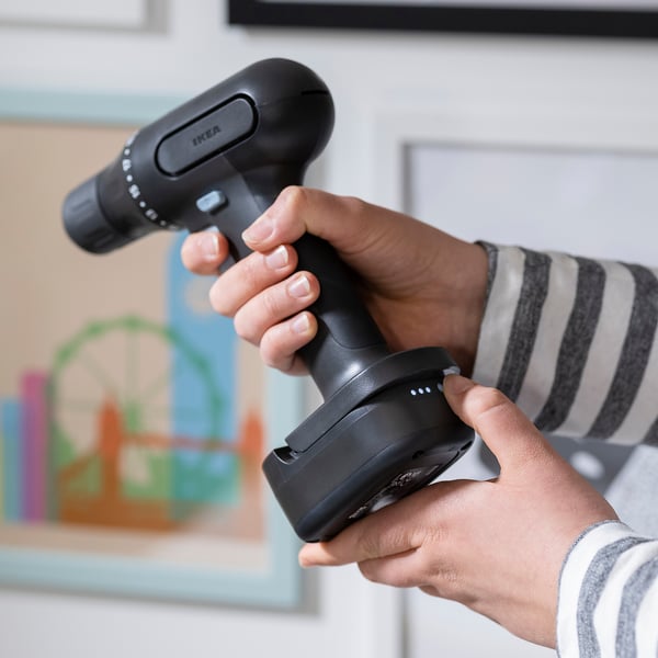 Person holding a cordless drill and extra battery, ready to work without interruption.