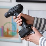 Person holding a cordless drill and extra battery, ready to work without interruption.