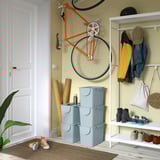 Entryway with orange bike, blue bins, and plant.