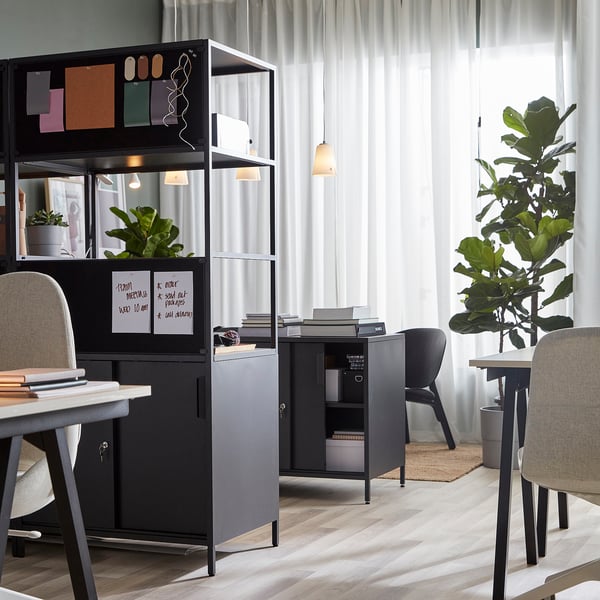 Modern office with double-sided cabinet, storage, whiteboard, plants, chairs.