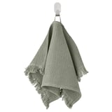 Green VALLASÅN towel, soft cotton blend, textured waffle shape, hangs from wall hook.