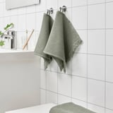 VALLASÅN light green towels hang near sink, soft and absorbent, seen with toothbrush and soap.