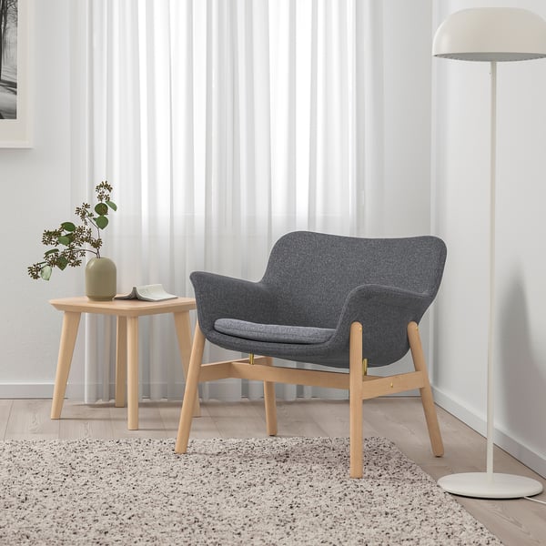 VEDBO gray armchair on wood floor with side table and lamp.