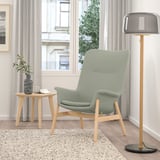Living room with green VEDBO armchair, side table, lamp, and plants. Cozy and inviting with high back for privacy.