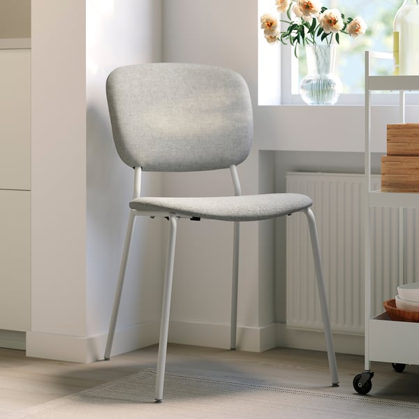VIHALS light grey minimalist chair with padded seat, near radiator and flowers.