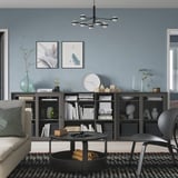Modern living room with black bookcase, decor, and cozy seating.