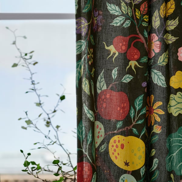 Green curtains with floral patterns hang by a window, filtering light for privacy and a casual look.