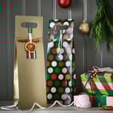 Two gift bags, gold with dried orange and green with polka dots, with striped ribbon and small gifts, festive setup.