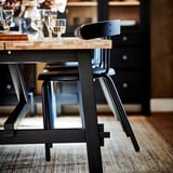 Modern black metal chair with wooden seat, perfect for dining spaces.