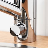 Modern chrome faucet mounted on wooden counter, showcasing sleek design and durable materials.